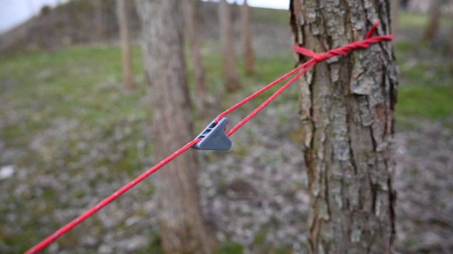 Připevnění ke kmeni stromu pomocí reflexní šňůry a táhla
