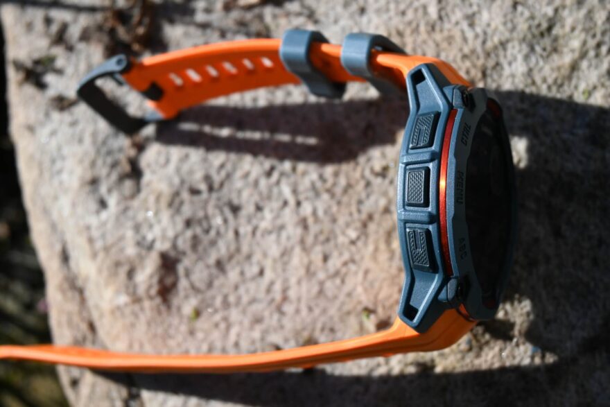 Detail tlačítek a kovového kroužku po obvodu hodinek GARMIN INSTINCT 3 SOLAR.