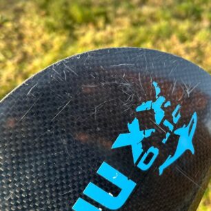 Detail hrany na nezáběrové straně listu na konci testování. Po osmi měsících provozu je pouze poškrábaná. Nejméně odolná je evidentně samolepka...