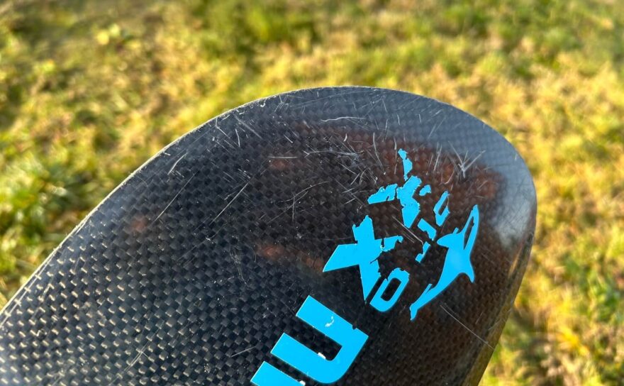 Detail hrany na nezáběrové straně listu na konci testování. Po osmi měsících provozu je pouze poškrábaná. Nejméně odolná je evidentně samolepka...