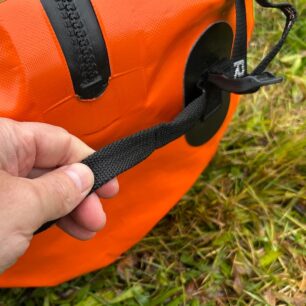 Na bocích tašky jsou jednoduchá madla z plochého popruhu.