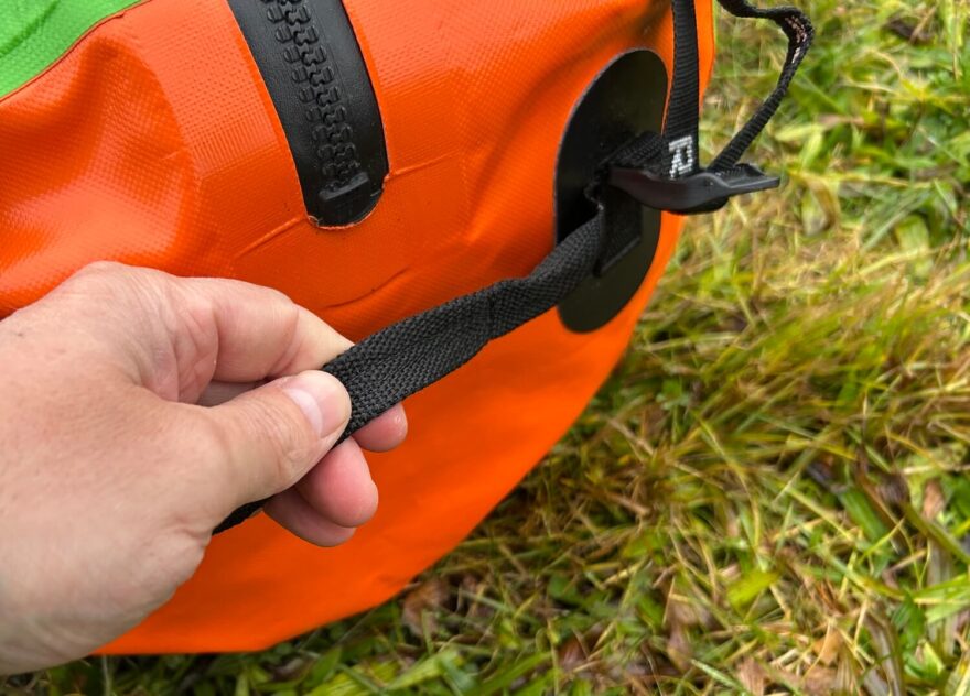 Na bocích tašky jsou jednoduchá madla z plochého popruhu.