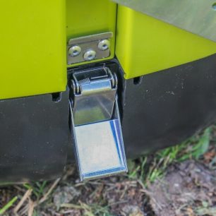 Plastový díl se ke grilu připíná dvěma kovovými přezkami